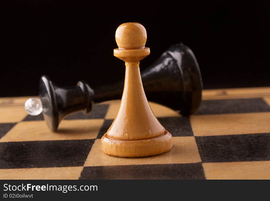 Black chess queen lays on a chessboard, black background. Black chess queen lays on a chessboard, black background