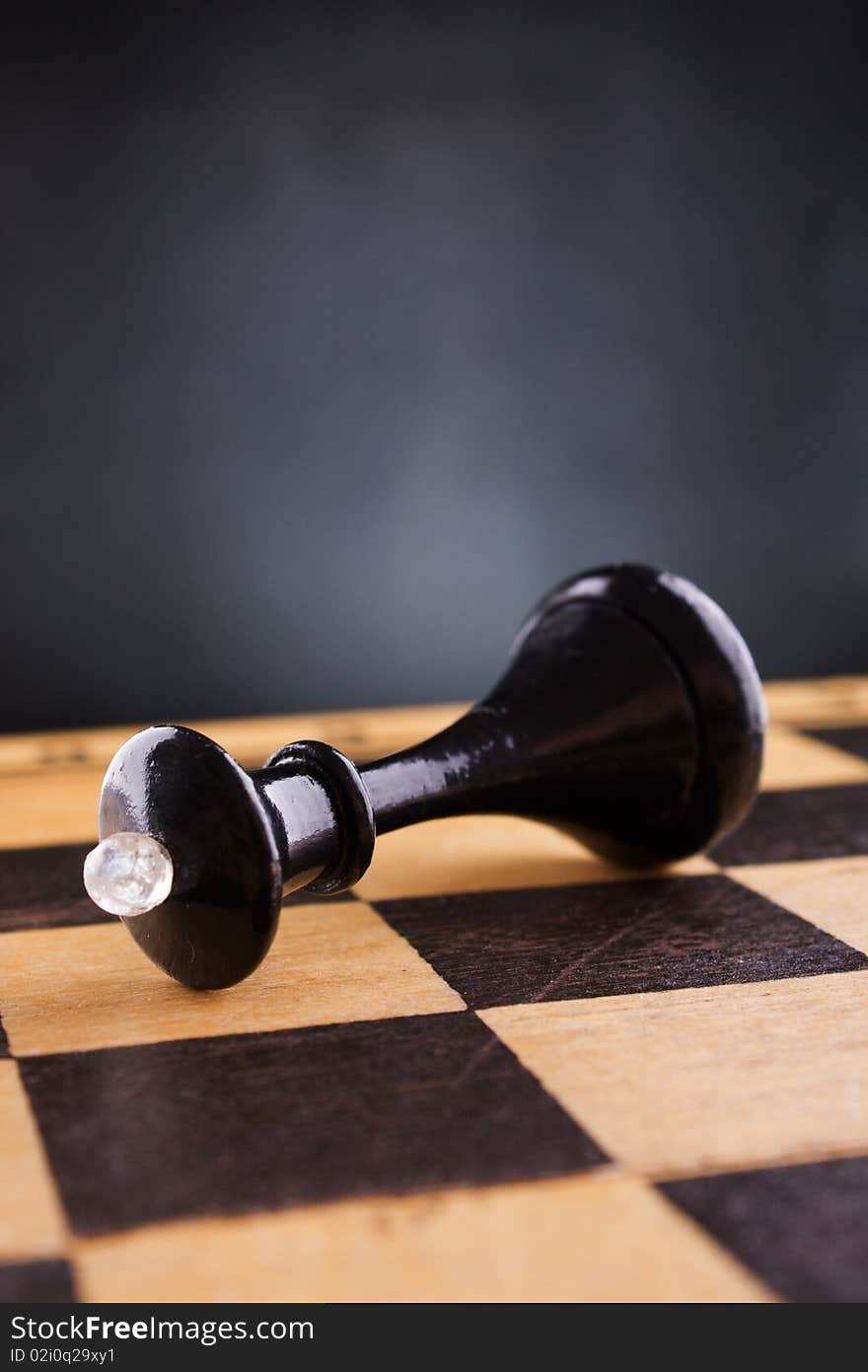 Black chess queen lays on a chessboard, black background