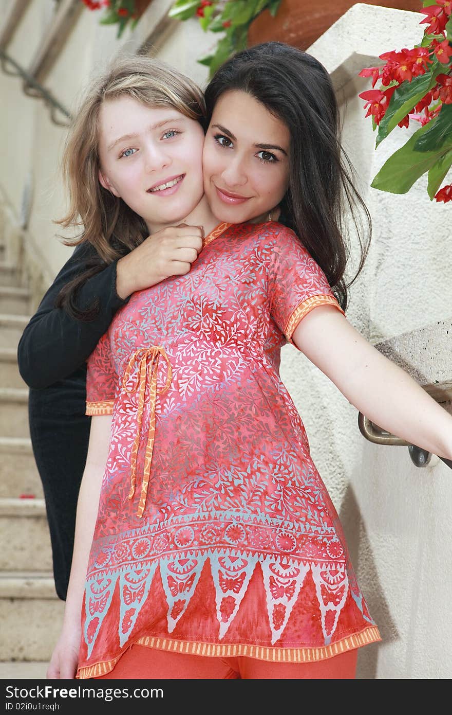 Young Woman and Young Teenager in a lifestyle pose on an outdoor staircase with flowers along the wall.