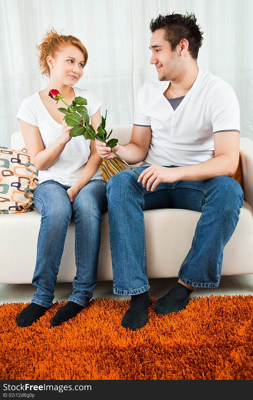 Young boy giving red rose to a beauty, young girl