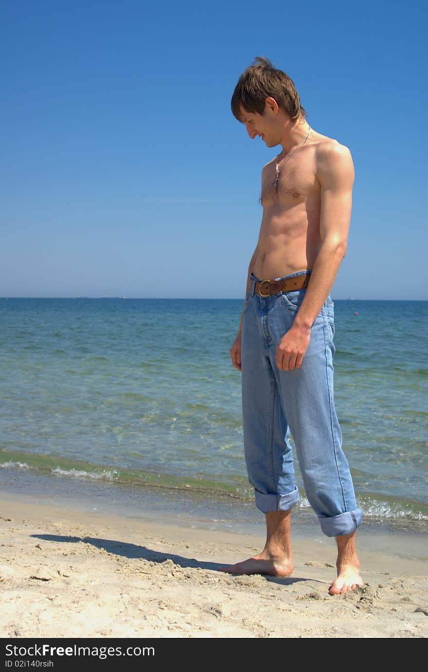 Man on the beach, who is sadly looking at his shadow. Man on the beach, who is sadly looking at his shadow