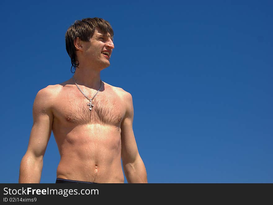 Man on the beach on a blue sky background. Man on the beach on a blue sky background