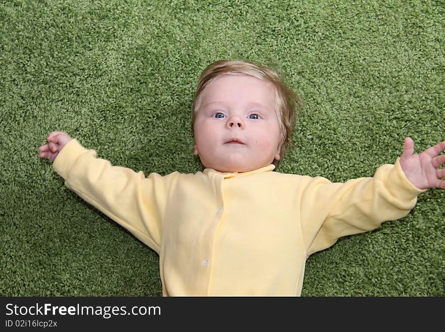 Nice baby boy greetings with open arms on a green fluffy cover