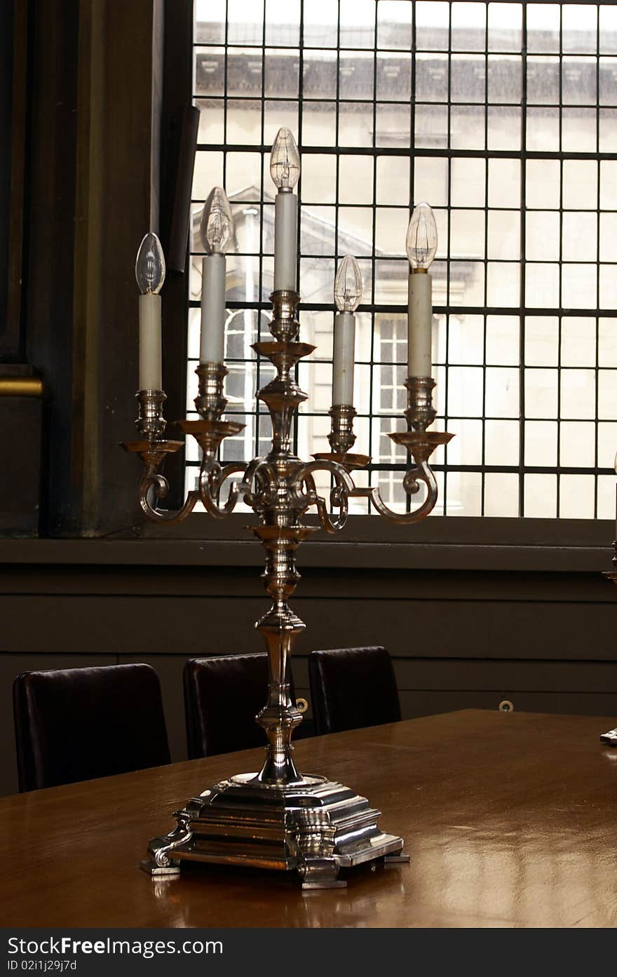 Candlestick with five candles-bulbs on wooden table in dining-room of old royal naval college, Greenwich, London, UK. Candlestick with five candles-bulbs on wooden table in dining-room of old royal naval college, Greenwich, London, UK.