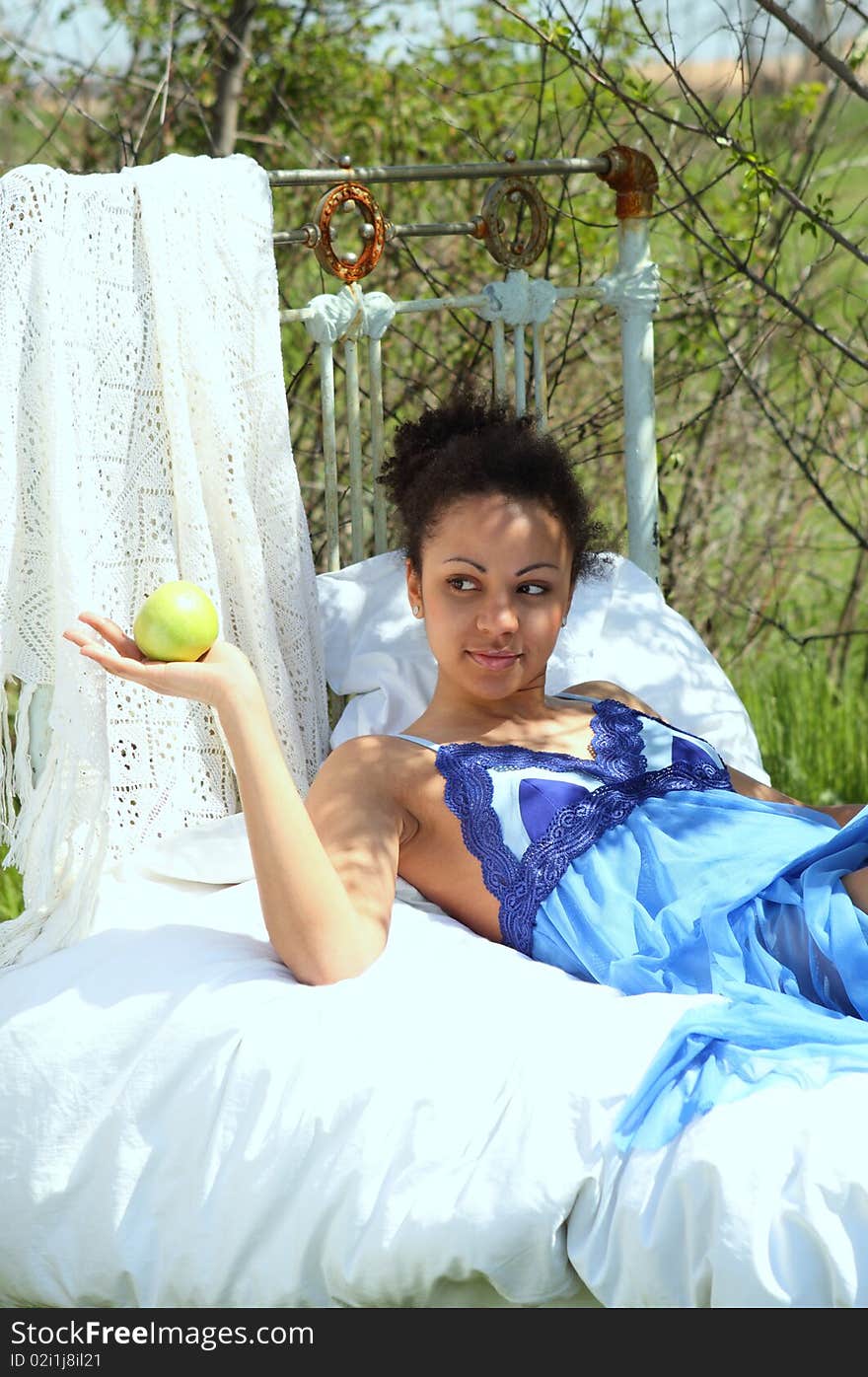 A beautiful mixed race African American girl with apple in the garden