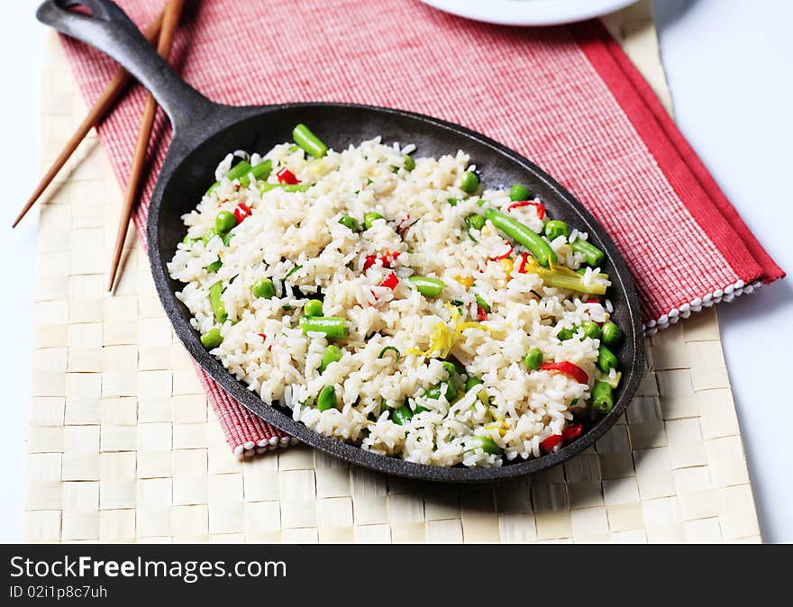 Rice and mixed vegetables stir fried in a skillet. Rice and mixed vegetables stir fried in a skillet