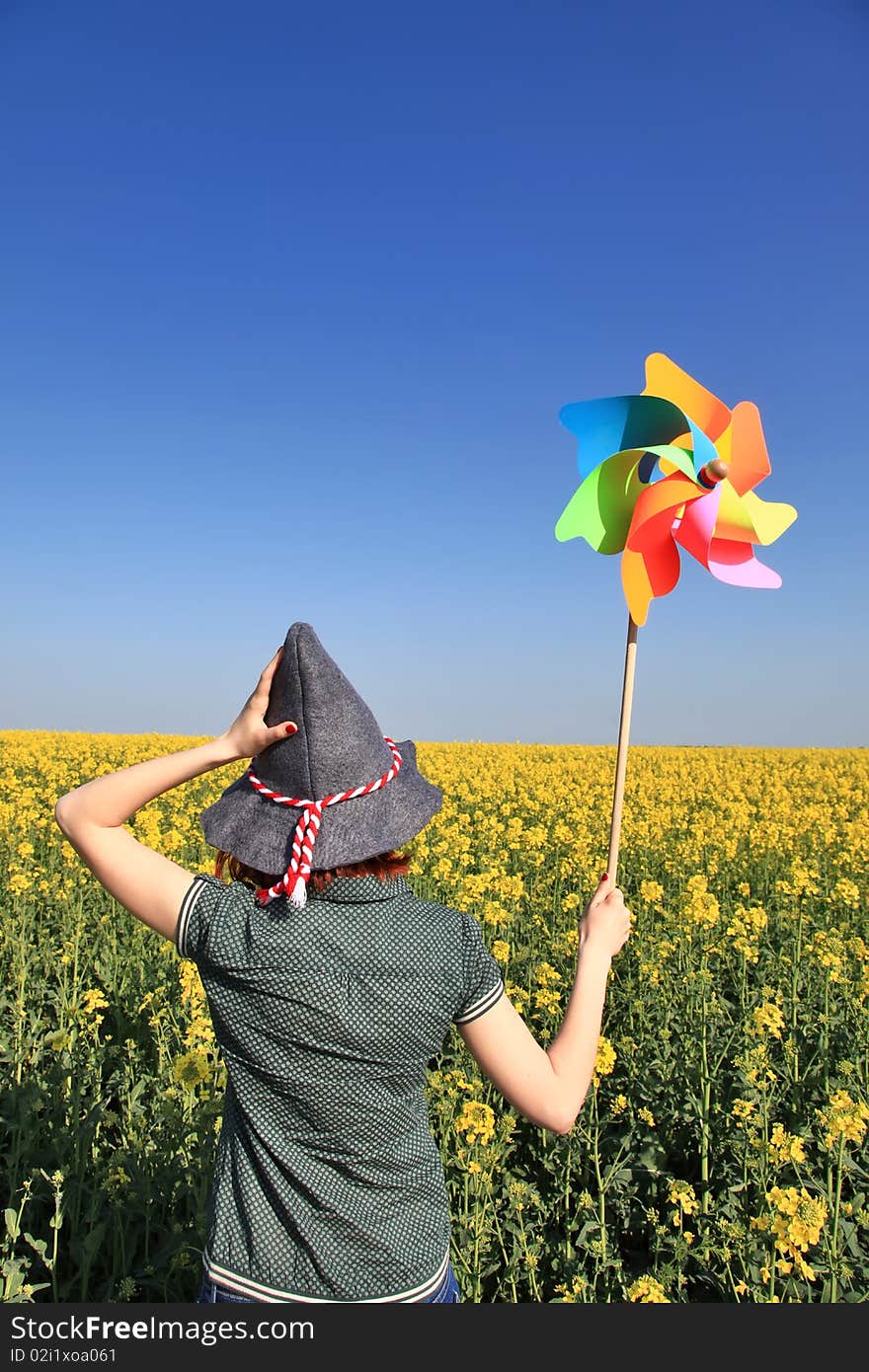 Girl in cap with wind turbine at rape field. Odessa, Ukraine.