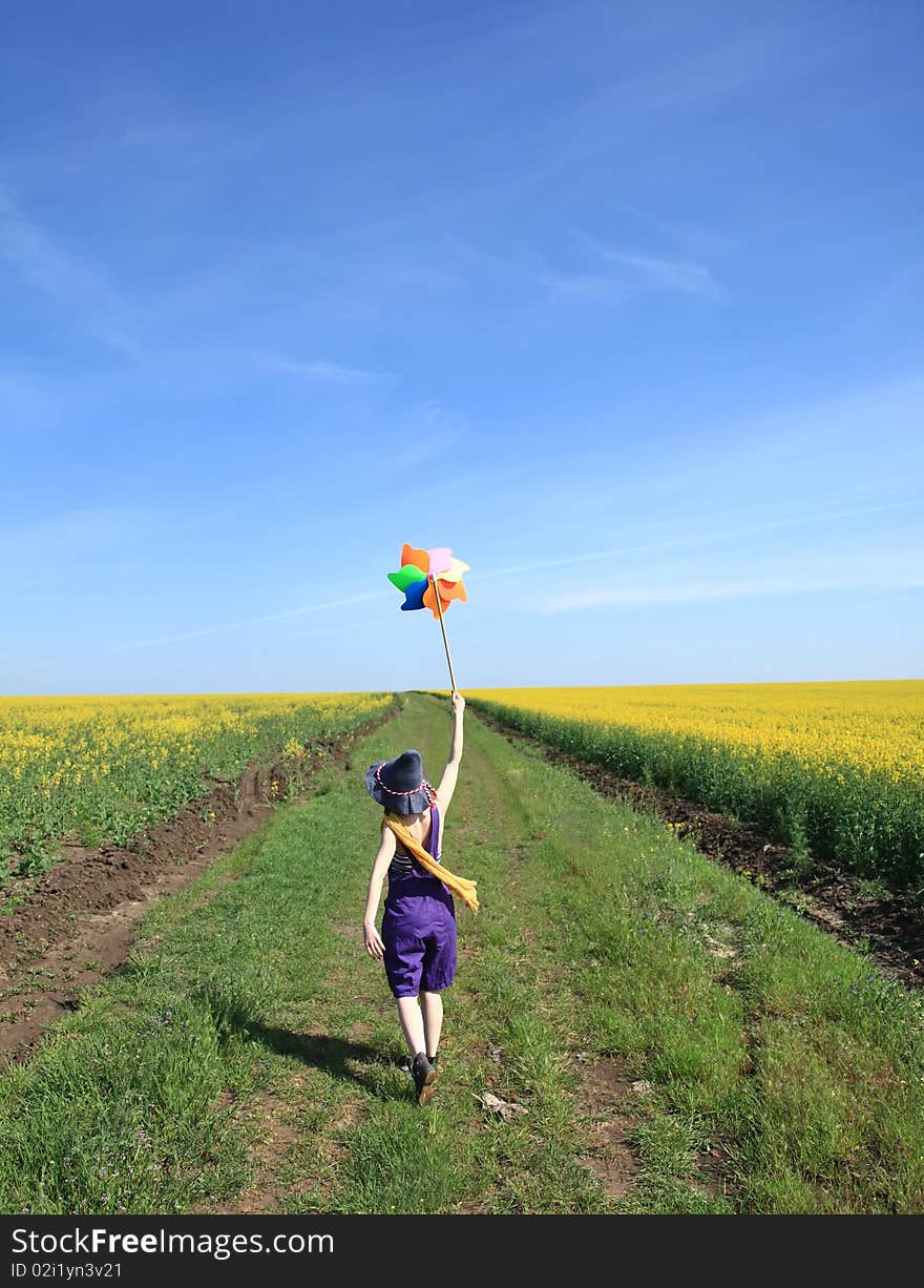 Girl with wind turbine at rape field.