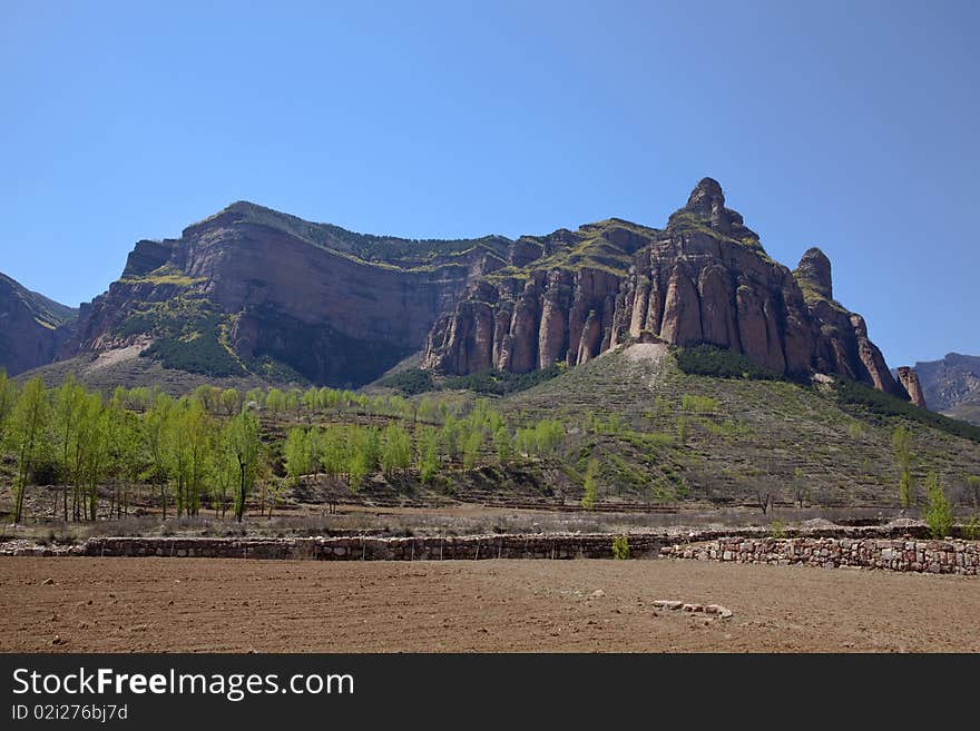 The uncultivated fields at the foot of the rocky mountains in China. The uncultivated fields at the foot of the rocky mountains in China