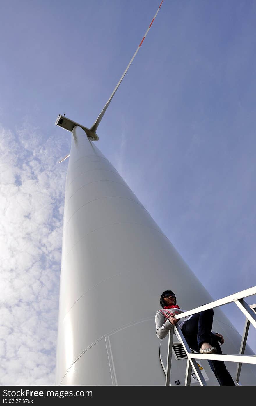 An image of young girl staying on stairs to wind turbine. An image of young girl staying on stairs to wind turbine