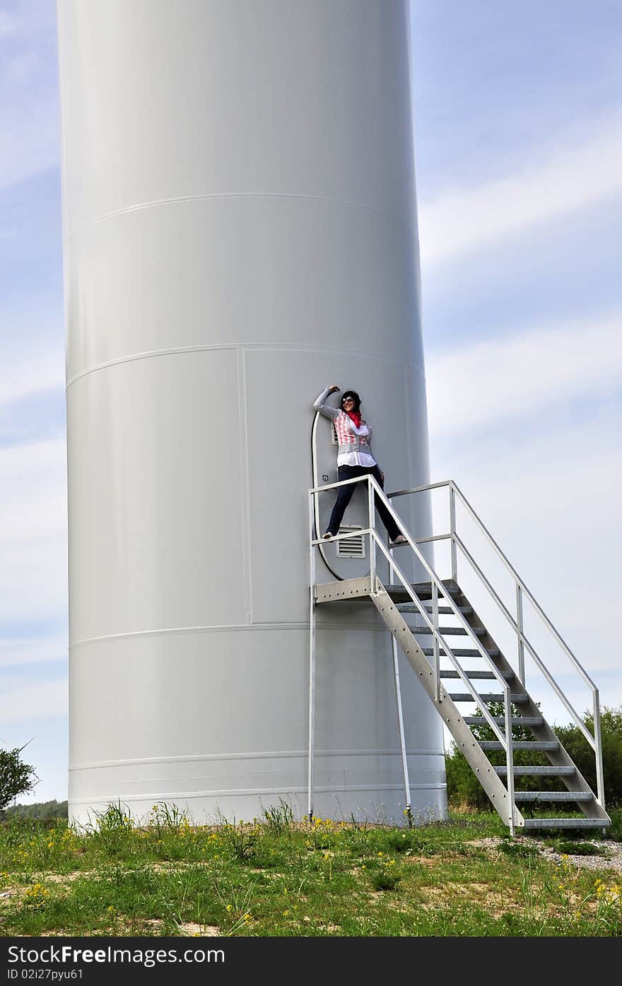 An image of young girl staying on stairs to wind turbine. An image of young girl staying on stairs to wind turbine