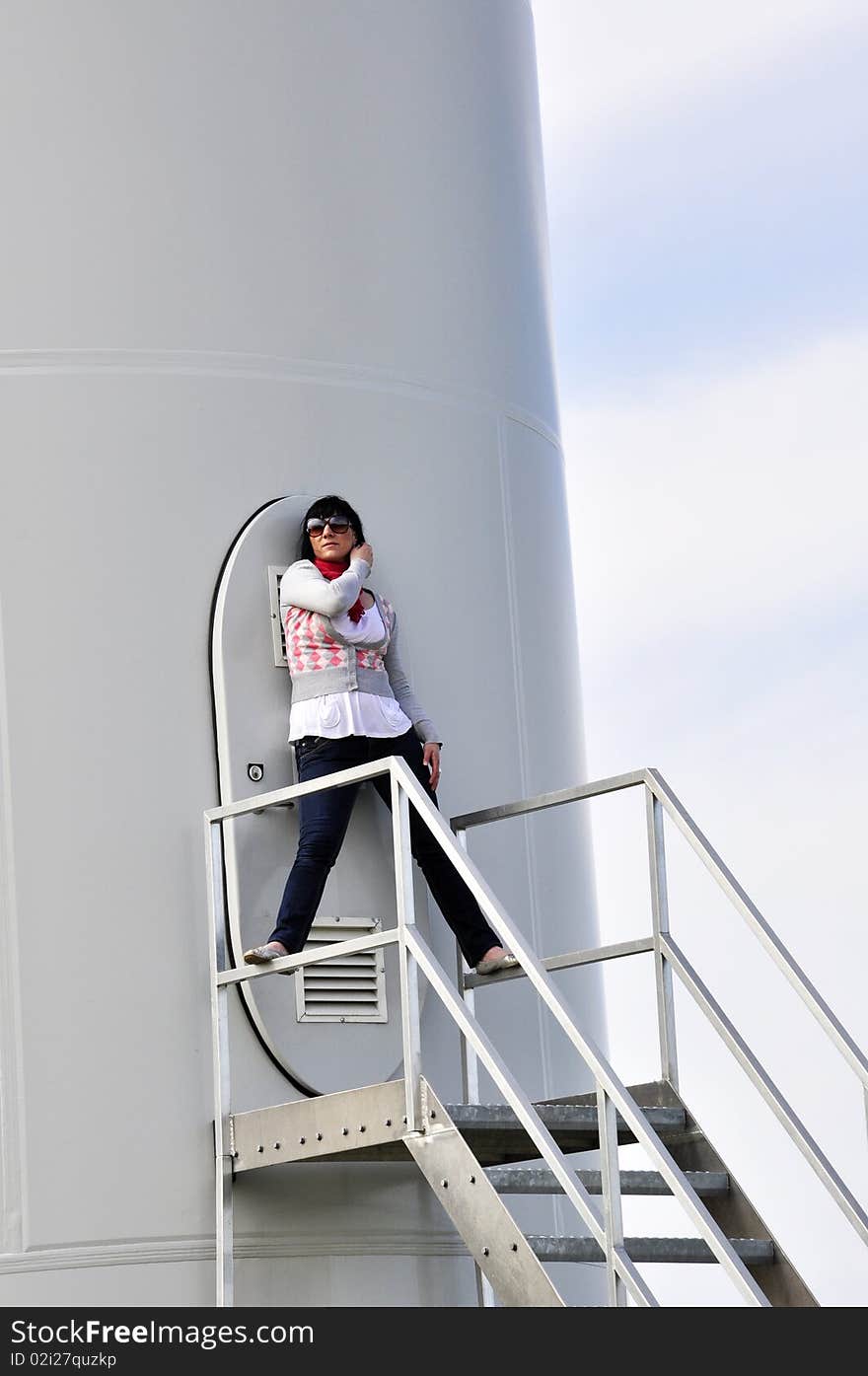 An image of young girl staying on stairs to wind turbine. An image of young girl staying on stairs to wind turbine