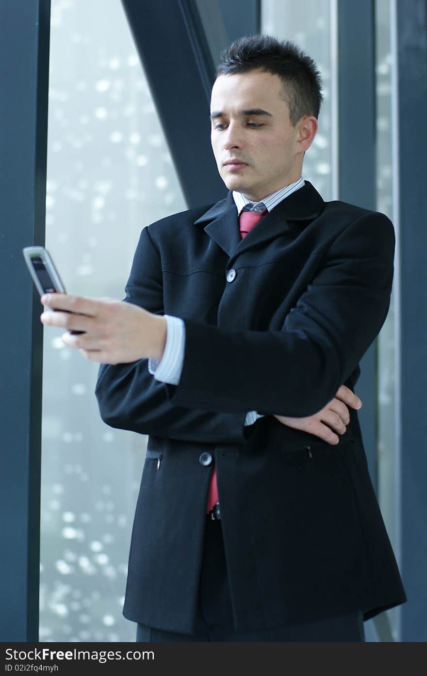 A young and handsome business man with a mobile phone. Image taken in a modern office. A young and handsome business man with a mobile phone. Image taken in a modern office.