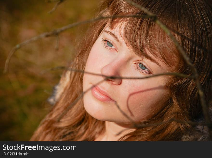 Portrait of a beautiful young woman with blue eyes, she is dreaming, there are shadows from the branch on her face. Portrait of a beautiful young woman with blue eyes, she is dreaming, there are shadows from the branch on her face