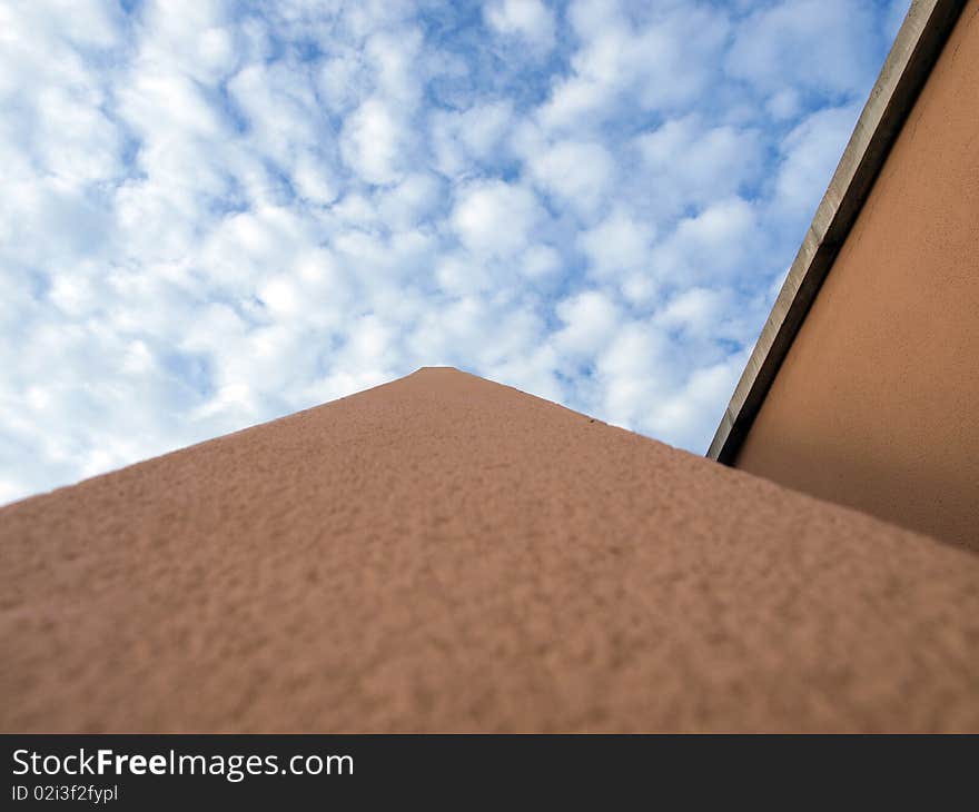 Close up view on part of building that points directly towards the heavens, with a blue sky with broken clouds. Close up view on part of building that points directly towards the heavens, with a blue sky with broken clouds.