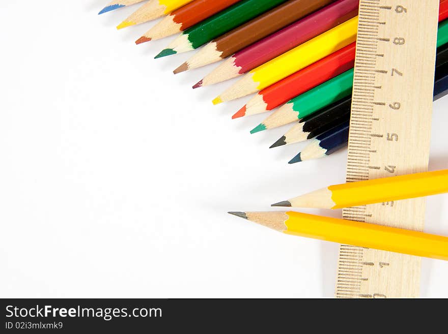 Colored pencils and a ruler on a white background