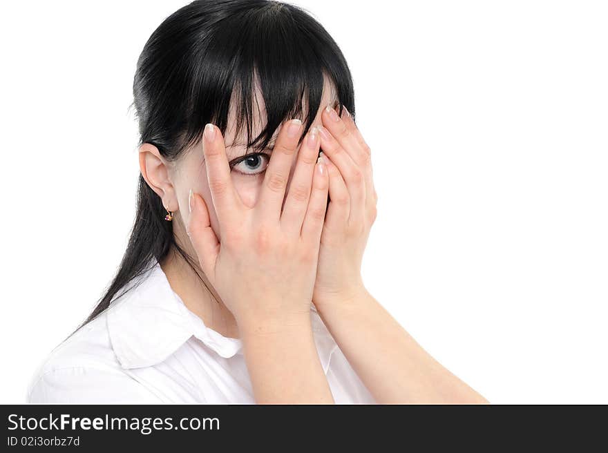 Young woman  is gazing through her fingers on a white background