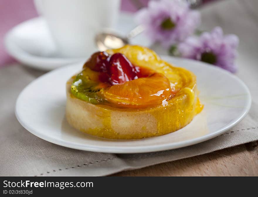 Fruitcake mini on a plate with fresh flowers on the background