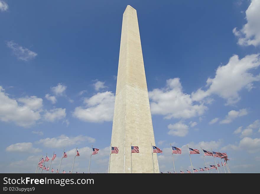 Washington monument in Washington DC against blue sky with american flags circling it