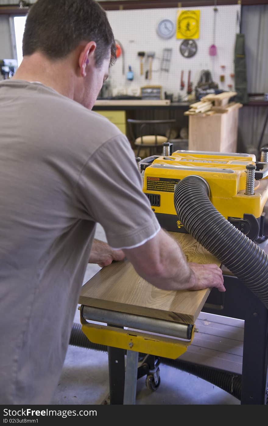 Man planing board with machine planer