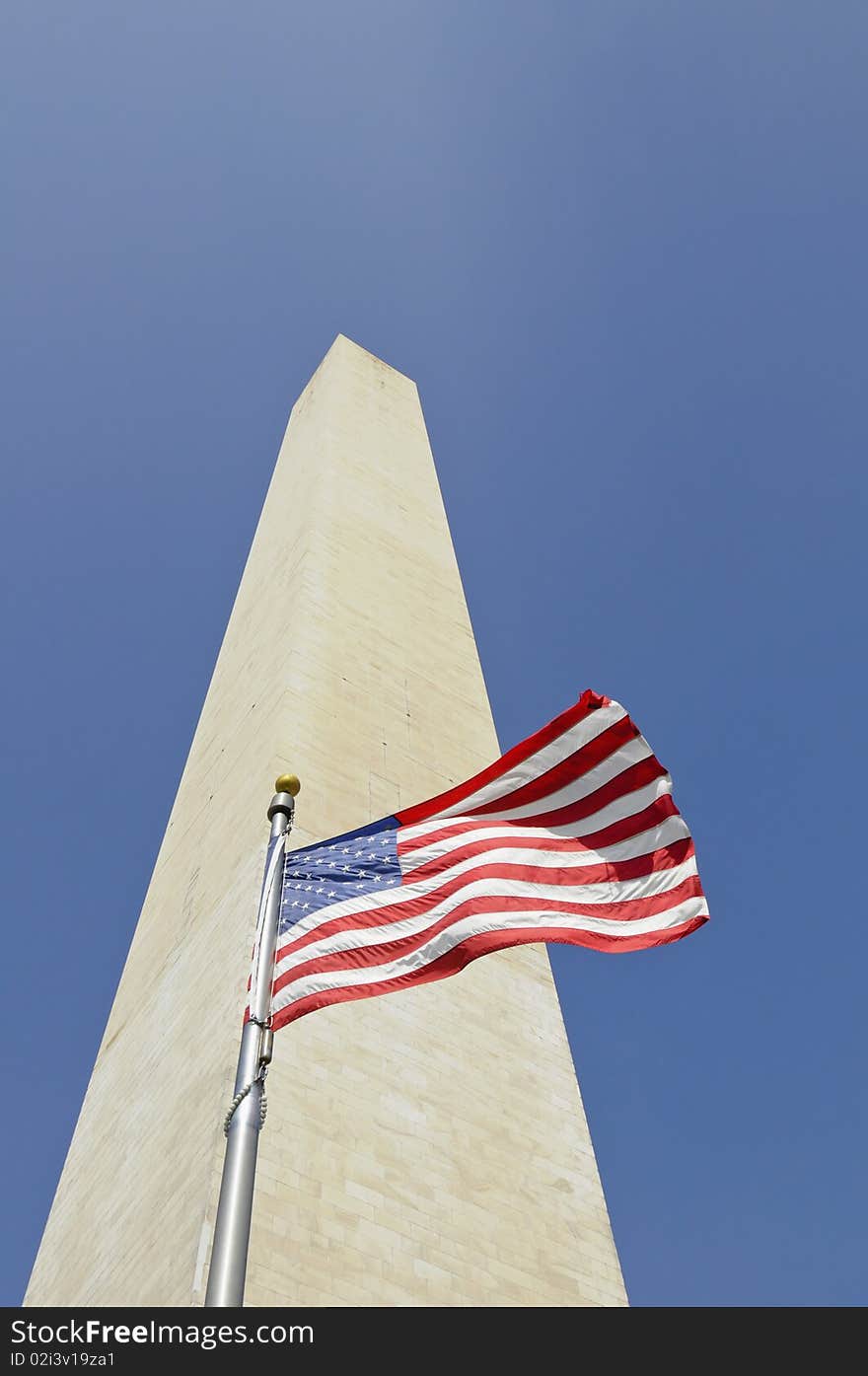 Washington monument in Washington DC against blue sky with american flag in front. Washington monument in Washington DC against blue sky with american flag in front