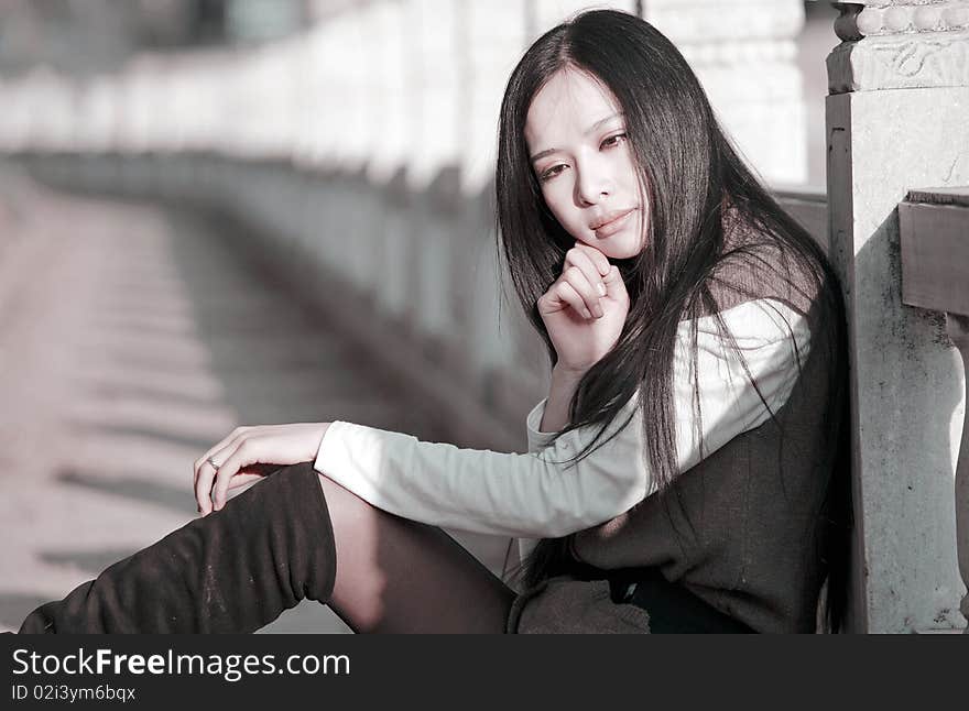 Young Asian woman is sitting outdoors and pondering in spring. Young Asian woman is sitting outdoors and pondering in spring.