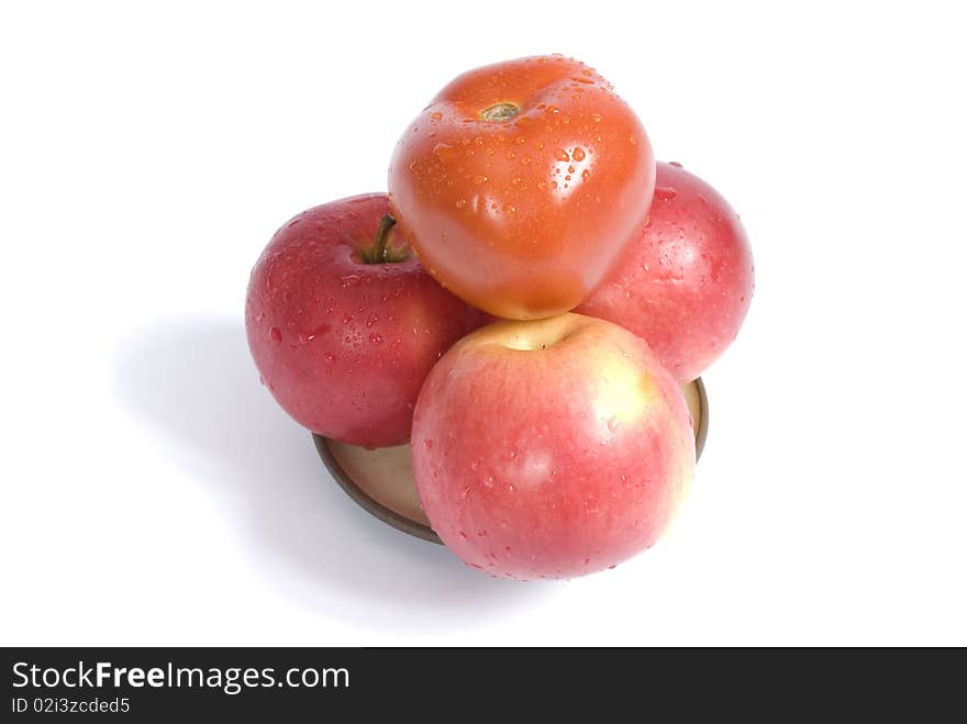 Ripe apples and red tomato coverd with drops of water on a plate, isolated on the white background. Ripe apples and red tomato coverd with drops of water on a plate, isolated on the white background