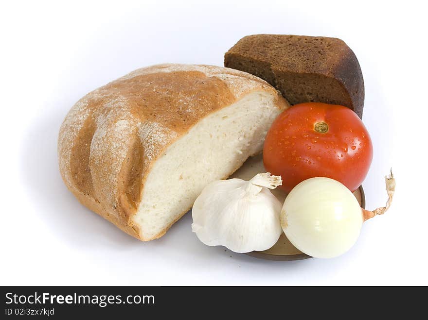 White and brown bread, and red ripe tomato, onion, garlic on a plate, isolated on the white background. White and brown bread, and red ripe tomato, onion, garlic on a plate, isolated on the white background