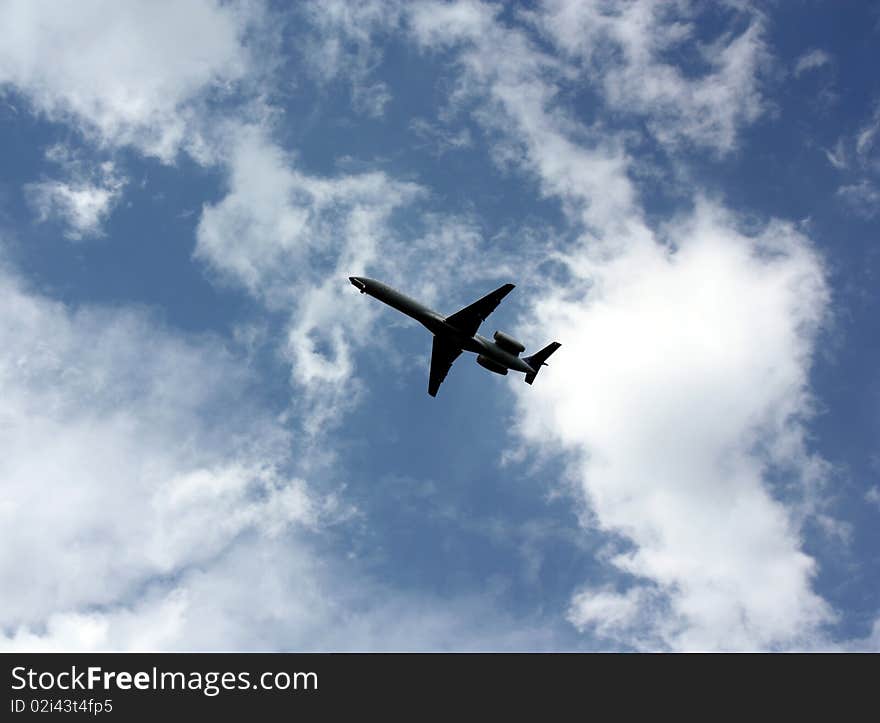 A jet airplane flying under small clouds while coming in to land. A jet airplane flying under small clouds while coming in to land.