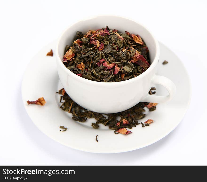 Cup filled with dried green tea leaves and rose petals