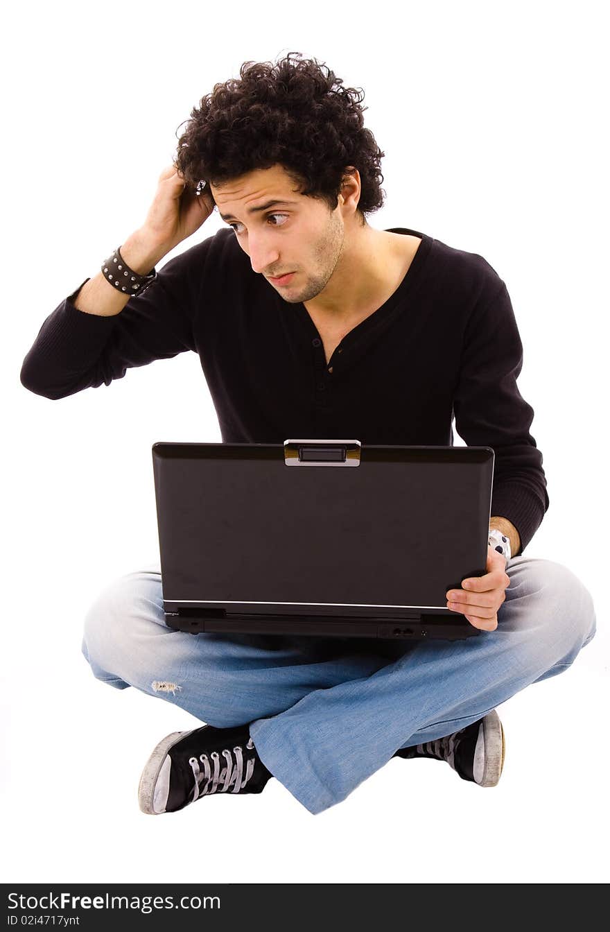 Pensive young man sitting on floor using laptop, isolated on white