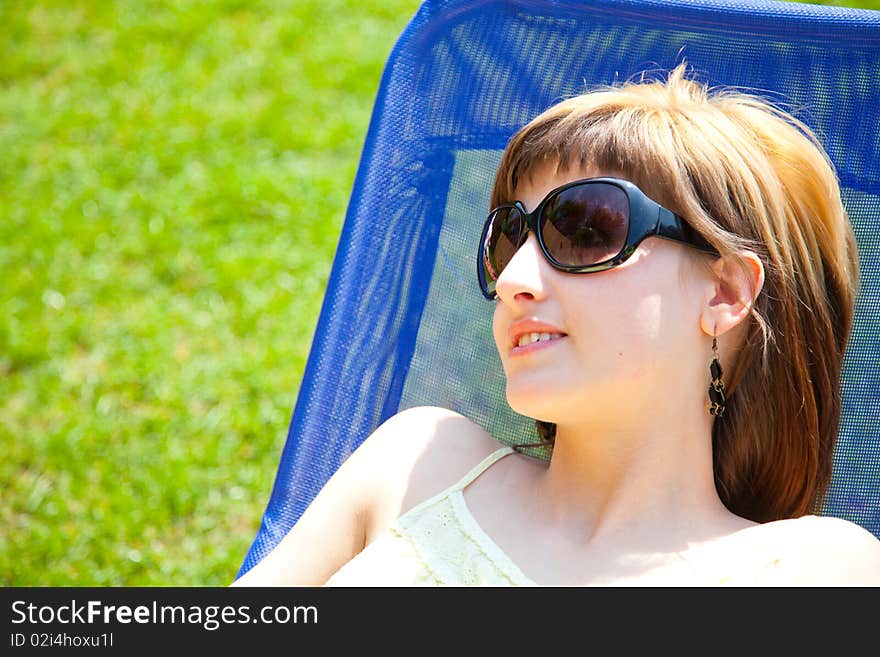 Beautiful young woman relaxing on a chair in the sun. Beautiful young woman relaxing on a chair in the sun.