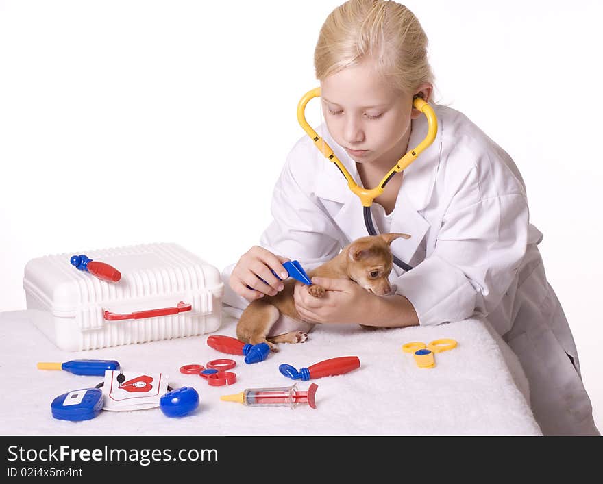 Young Blond Girl pretending to be a veterinarian uses tweezers on the puppy's paw. 5569. Young Blond Girl pretending to be a veterinarian uses tweezers on the puppy's paw. 5569