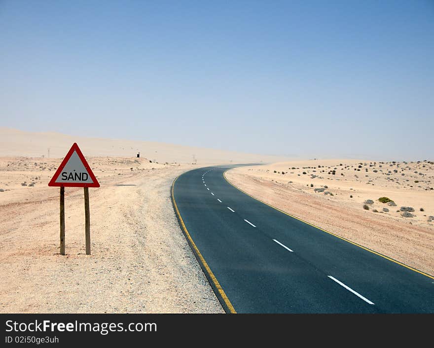 Warningsign SAND beside desolate highway against dusty blue sky, Namibia. Warningsign SAND beside desolate highway against dusty blue sky, Namibia.