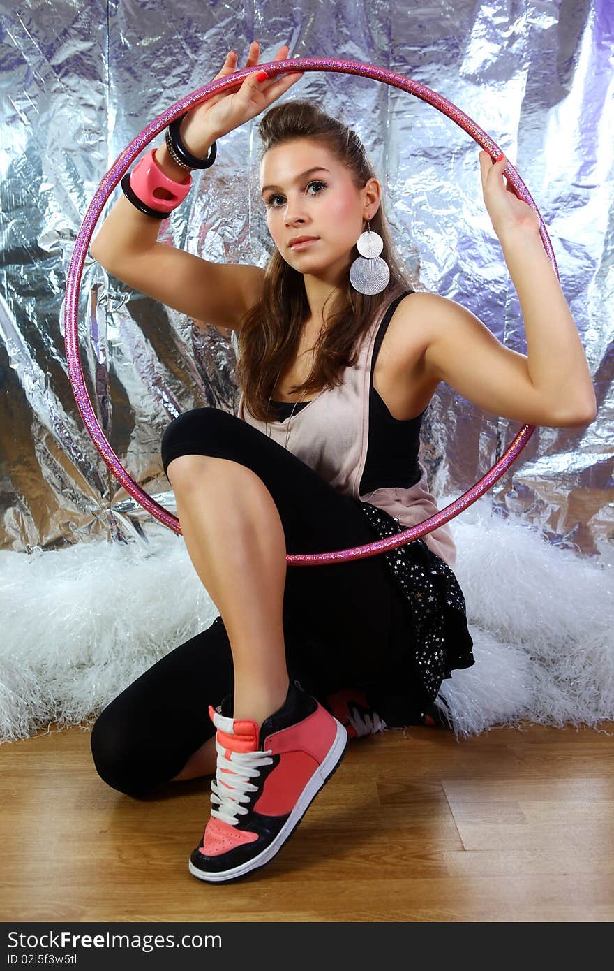 Shot of young and beautiful woman wearing pink shirt and black dress with glitter stars. She is holding pink glitter hoop. Shiny reflective background (Professional makeup and hair style). Shot of young and beautiful woman wearing pink shirt and black dress with glitter stars. She is holding pink glitter hoop. Shiny reflective background (Professional makeup and hair style).