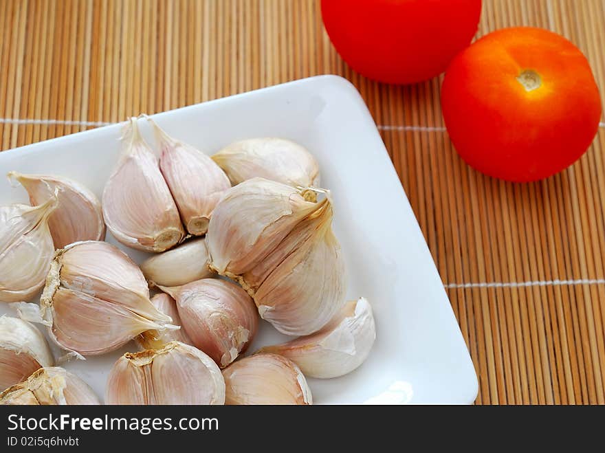 Many fresh white garlic cloves on white plate. Commonly used as seasoning and food ingredient in many Chinese cuisine. For food and beverage concepts. Many fresh white garlic cloves on white plate. Commonly used as seasoning and food ingredient in many Chinese cuisine. For food and beverage concepts.