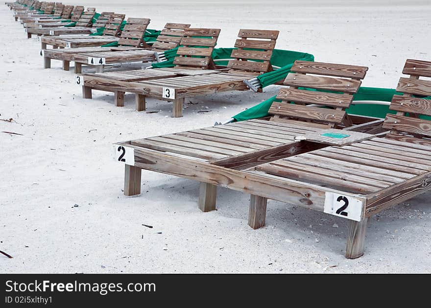 Row of wooden beach lounge chairs located on Florida's west coast.