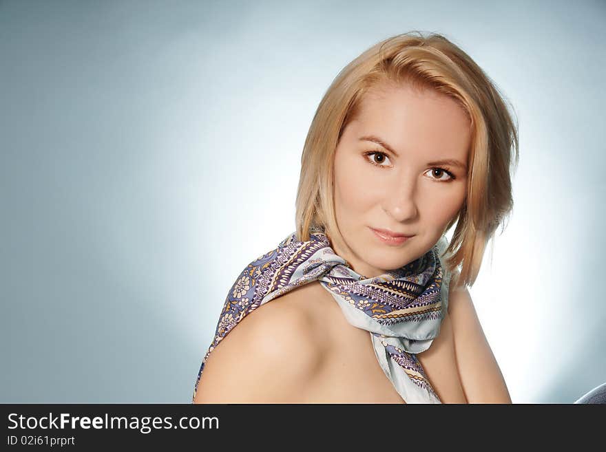 Potrrait of young attractive woman in scarf on blue background