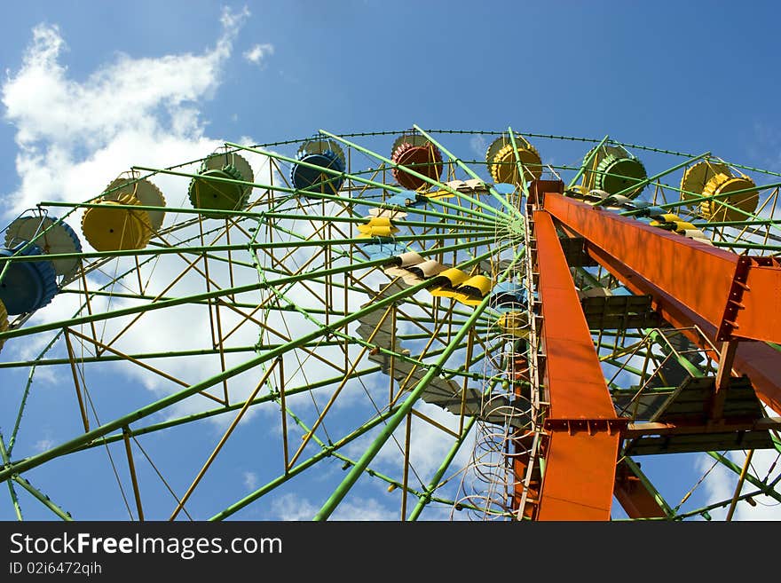 Ferris wheel against bright blue sky on amusement park