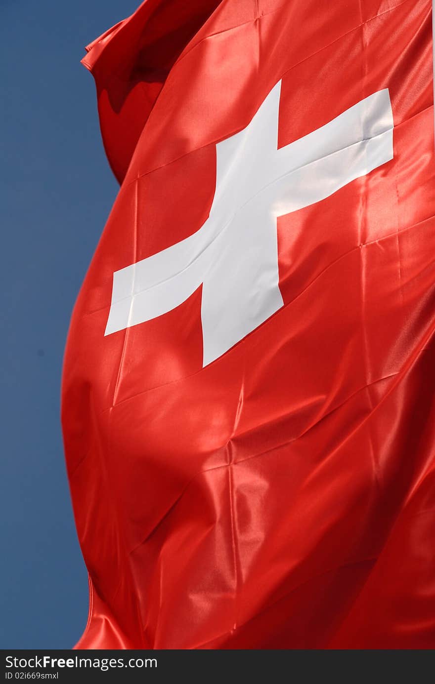 Flag of switzerland in the wind with blue sky. Flag of switzerland in the wind with blue sky