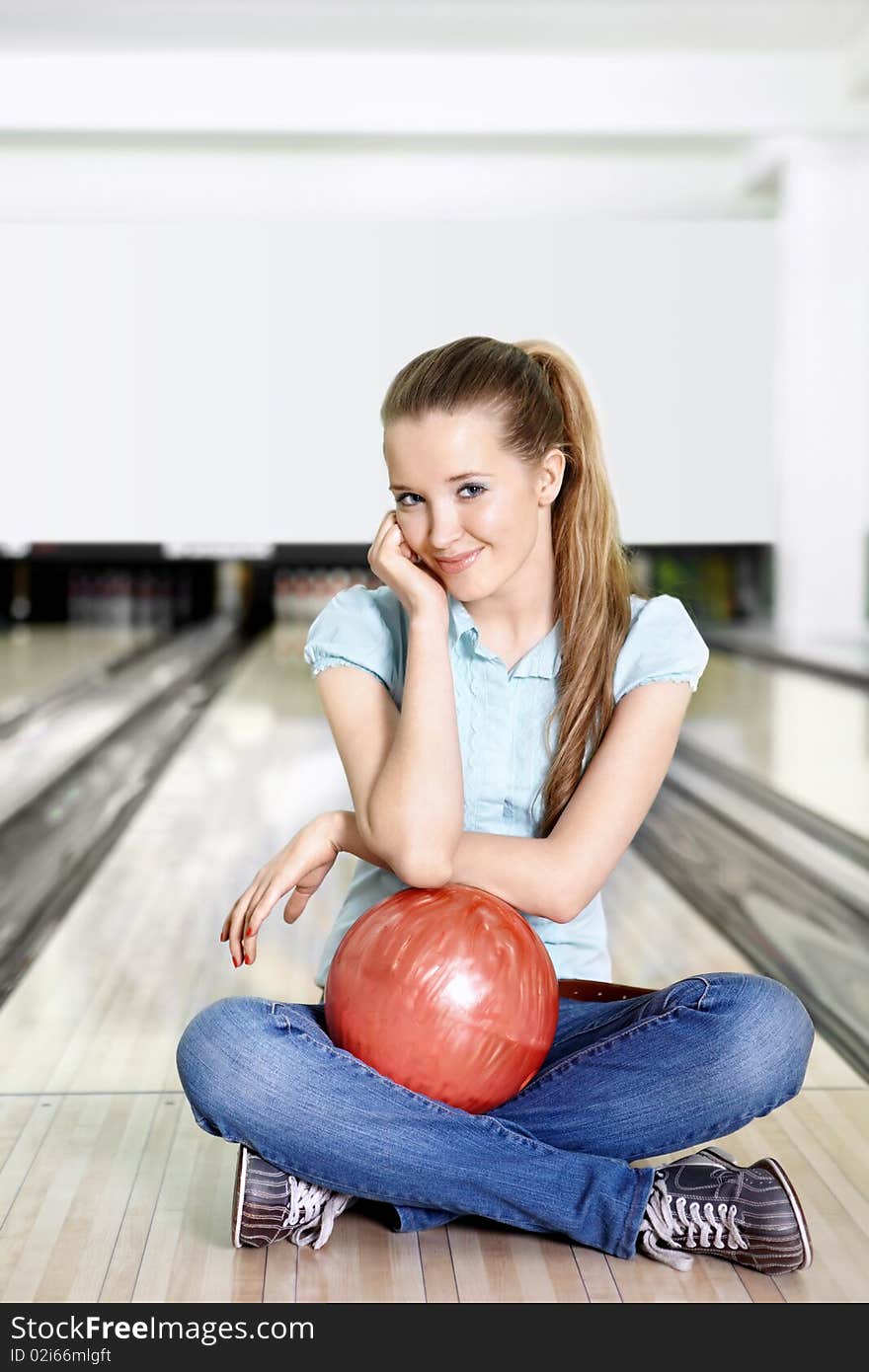 The young attractive girl with a sphere for bowling in the foreground. The young attractive girl with a sphere for bowling in the foreground