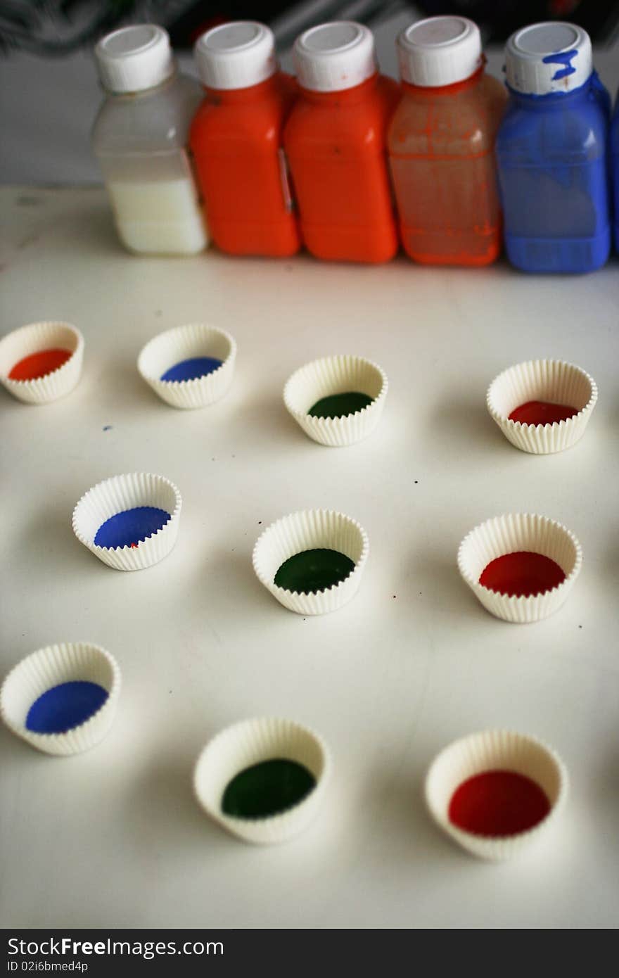 Colorful paint bottle and little paper cup