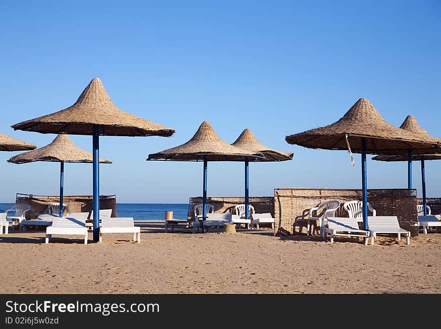 Deck chairs and umbrellas in tropical beach. Deck chairs and umbrellas in tropical beach