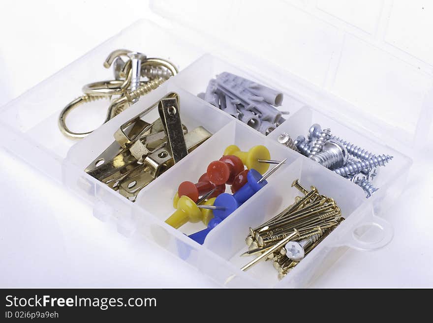 A plastic container with nails, pins, screws and other fittings for hanging objects. A plastic container with nails, pins, screws and other fittings for hanging objects