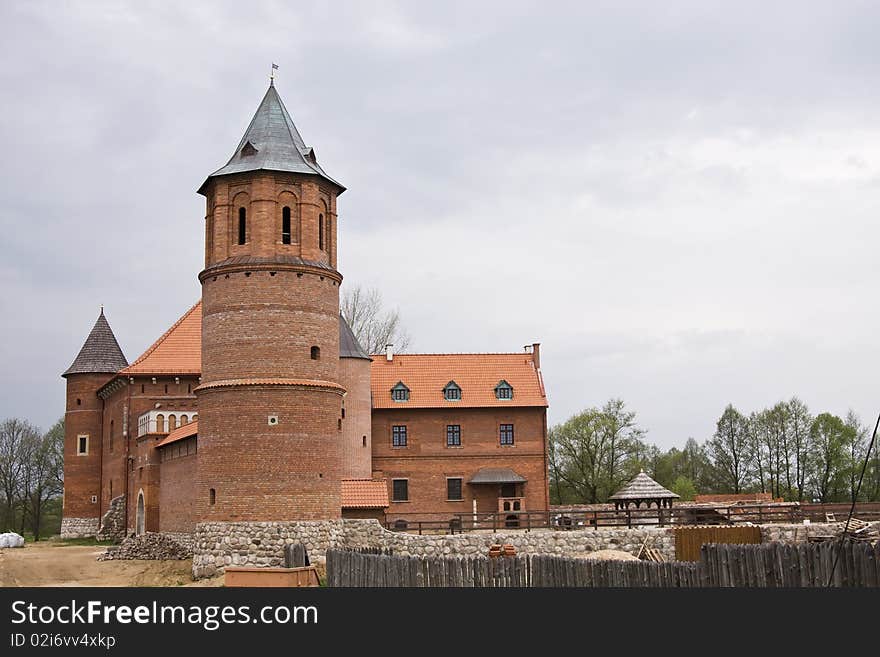 Big castle under construction surrounded by trees on cloudy sky