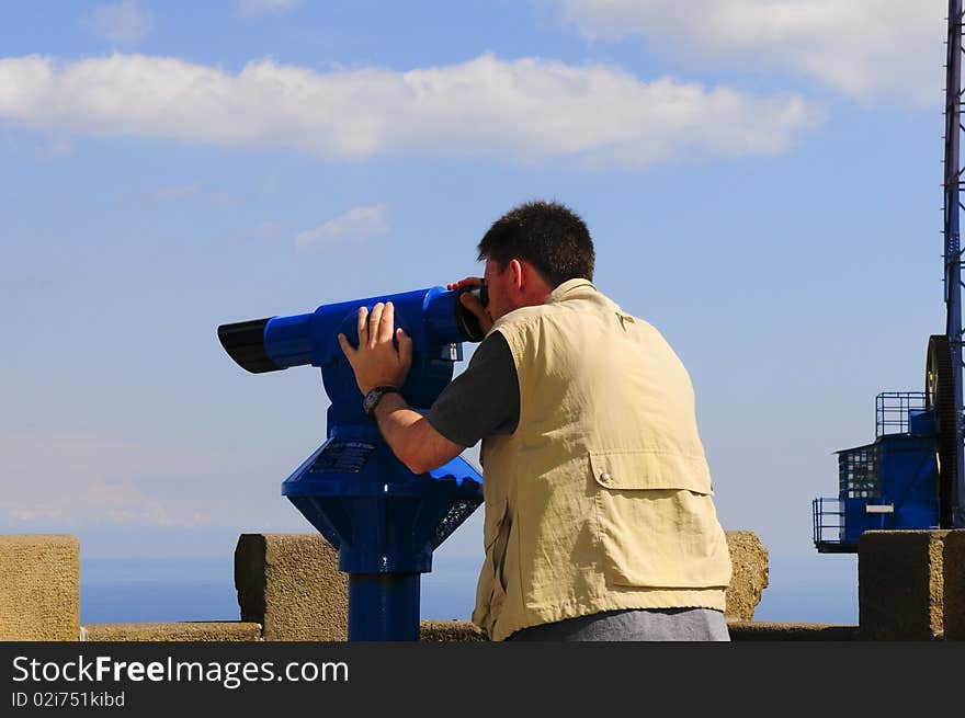 Man looking through a coin operated binoculars