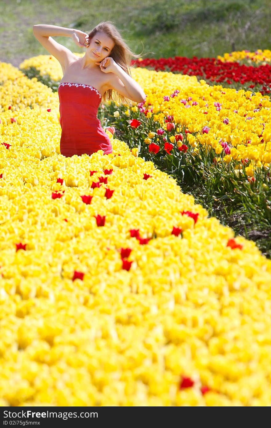 Young beautiful girl in yellow and red tulips