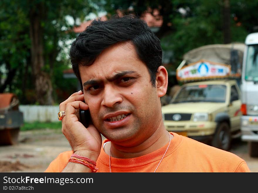 A young man showing expressions of extreme disturbance and stress while taking a phone call. A young man showing expressions of extreme disturbance and stress while taking a phone call.