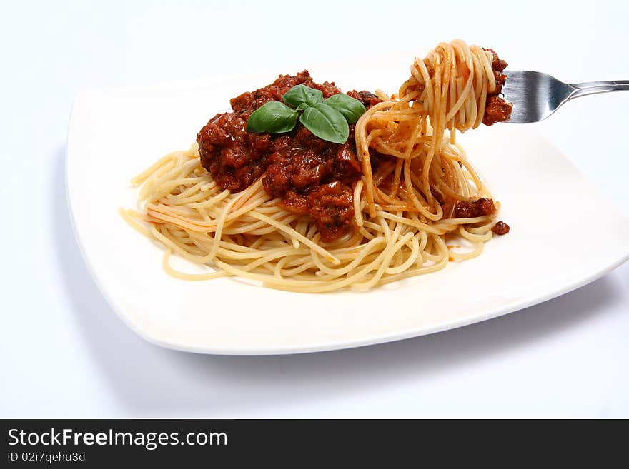 Spaghetti bolognese on a plate and some on a fork on white