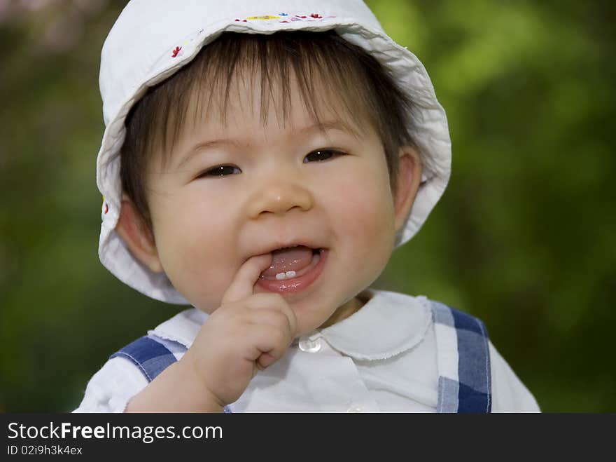 Cute little girl sucking finger in garden